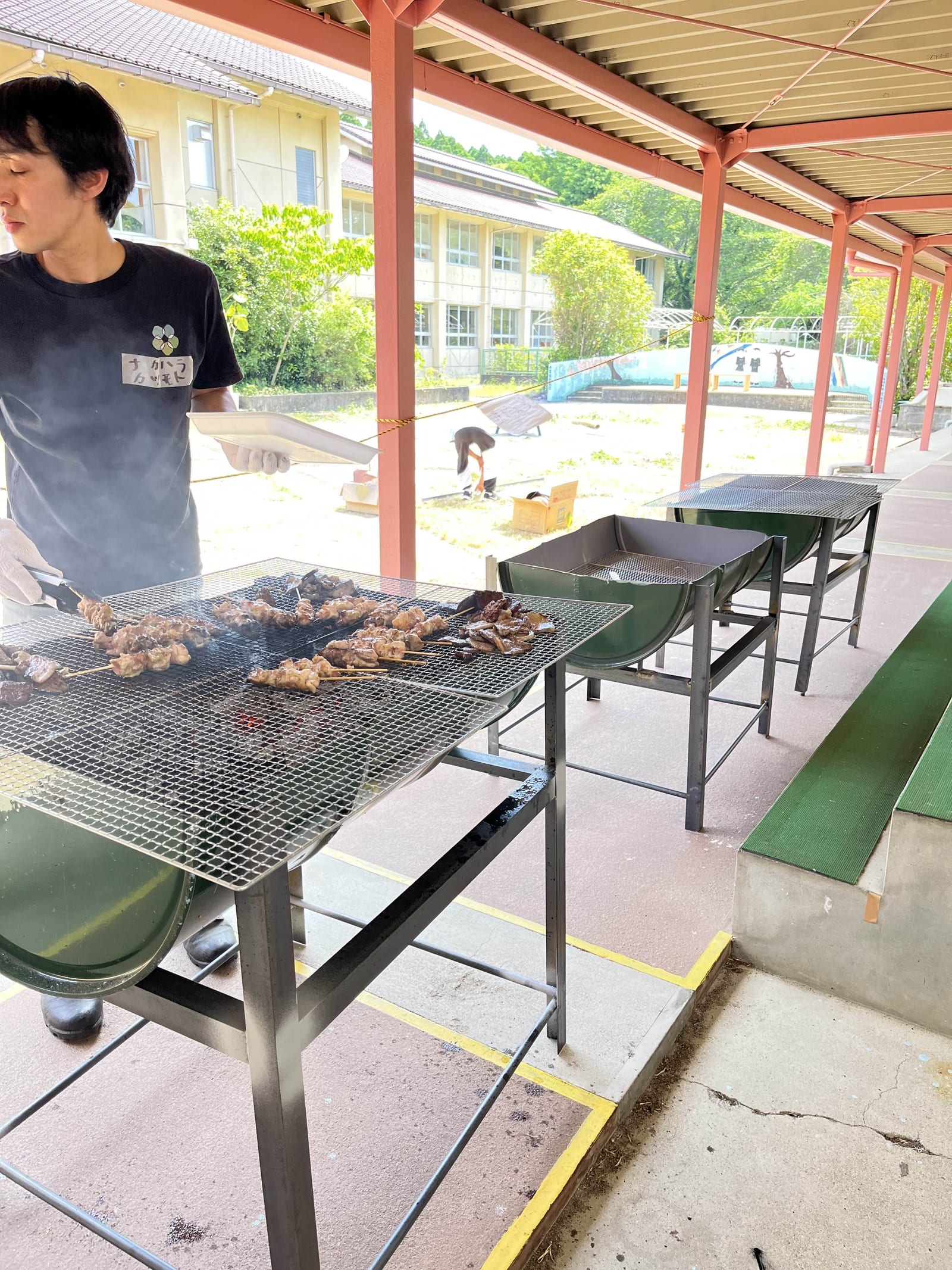 屋根の下に置いたドラム缶コンロで肉を焼いているところ