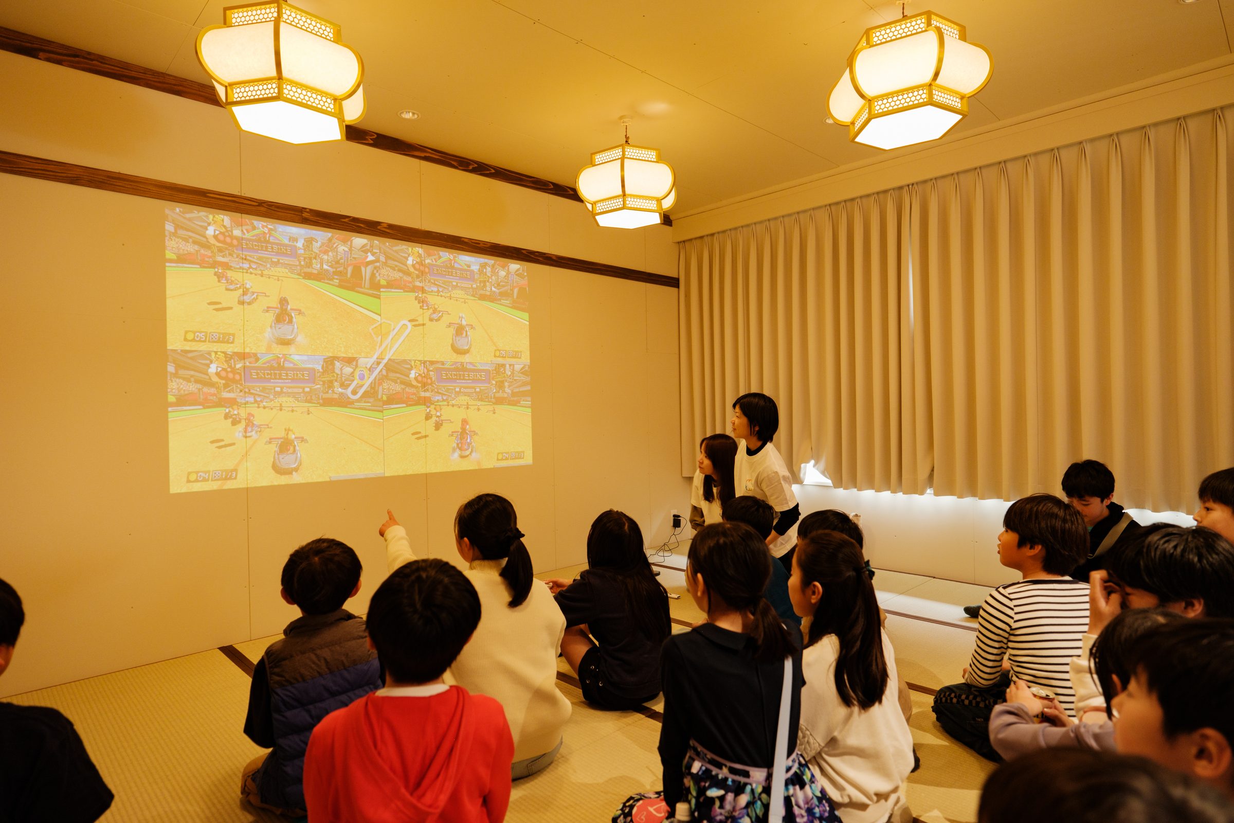 YAMAGA BASE の合宿／和室でゲーム画面を眺める子どもたちの後ろ姿